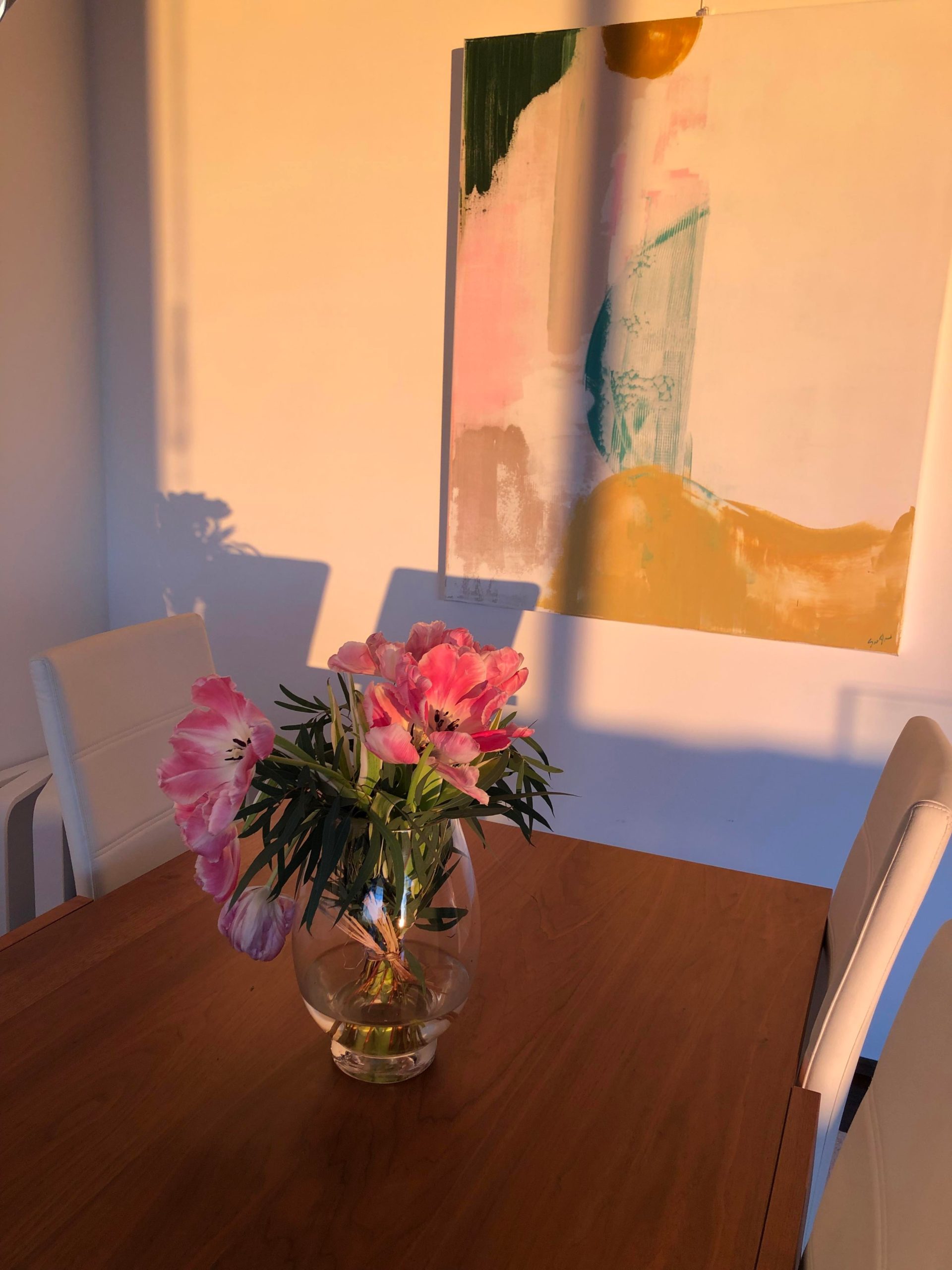 Valo osuu ruokapöydän kukkiin ja seinän tauluun