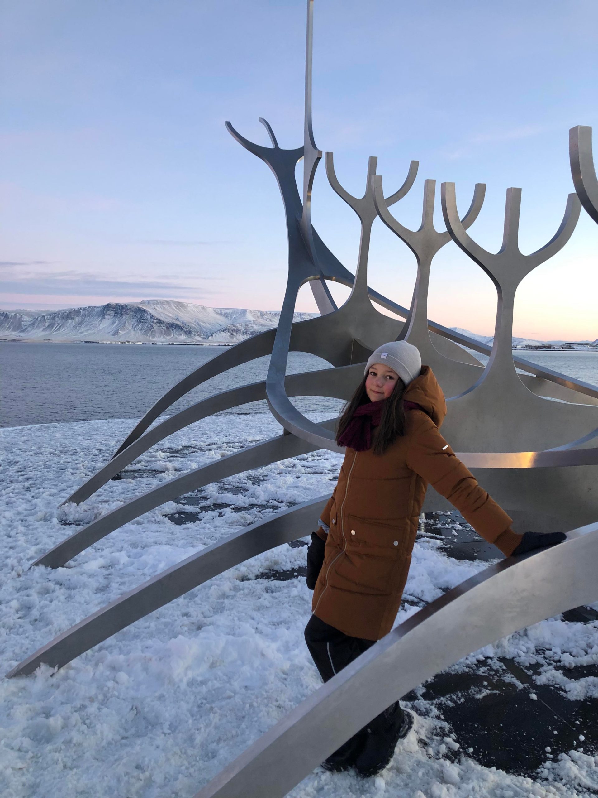 Tyttö nojaa patsaaseen Reykjavikissa