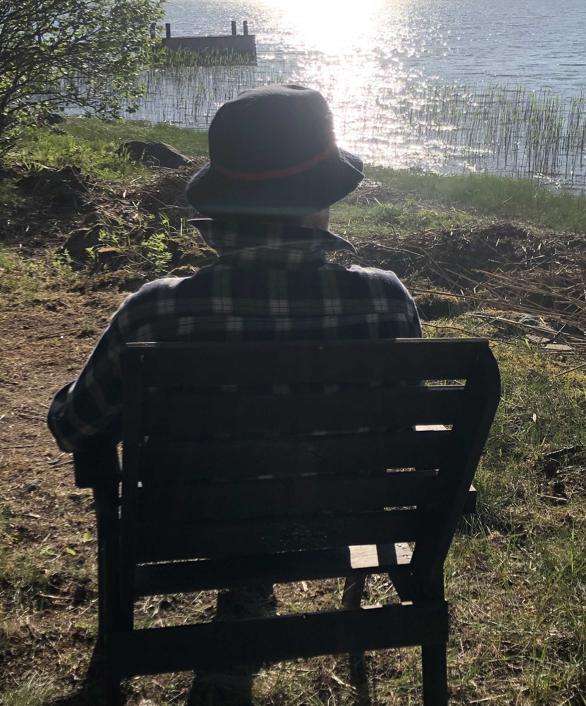 Mies istuu ja katsoo auringonlaskua