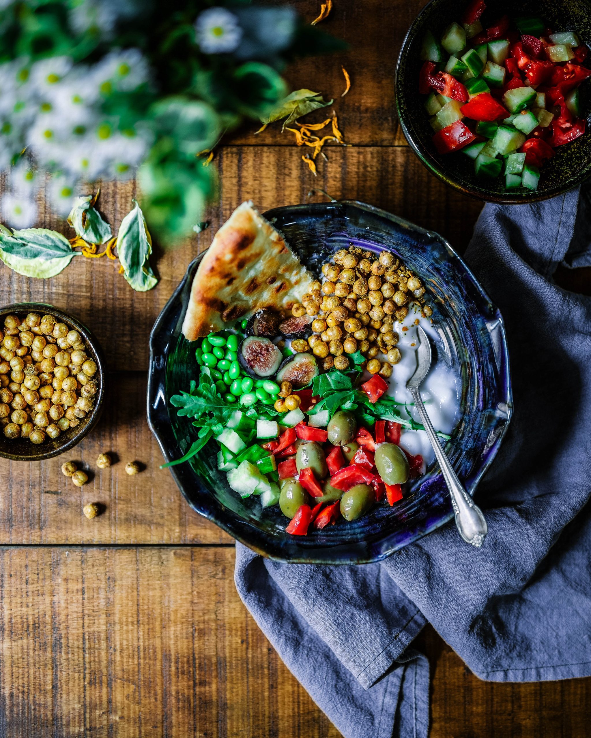 Kuvassa näkyy kulhollinen värikästä kasvisruokaa. Kulho on puisella pöydällä ja sen alla on siniharmaa lautasliina.